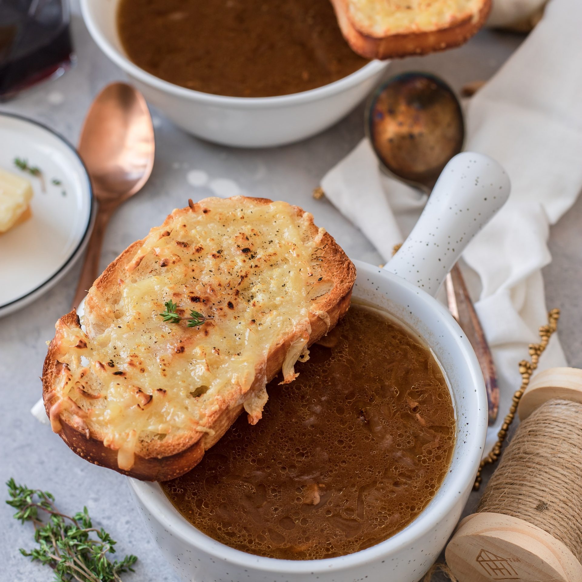 onion soup in a small bowl with a slice of bread with gratinated cheese on it.