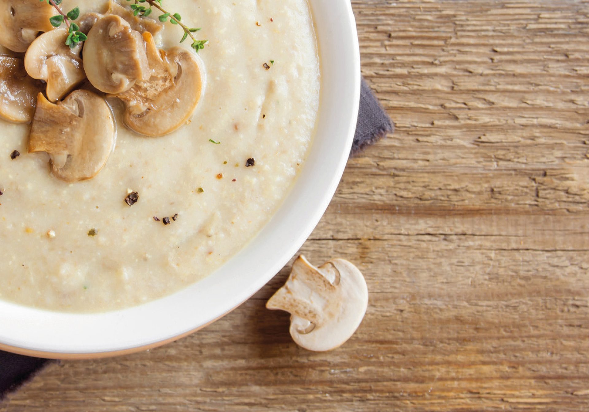 beige puree with mushrooms and thyme in a bowl on a wooden table