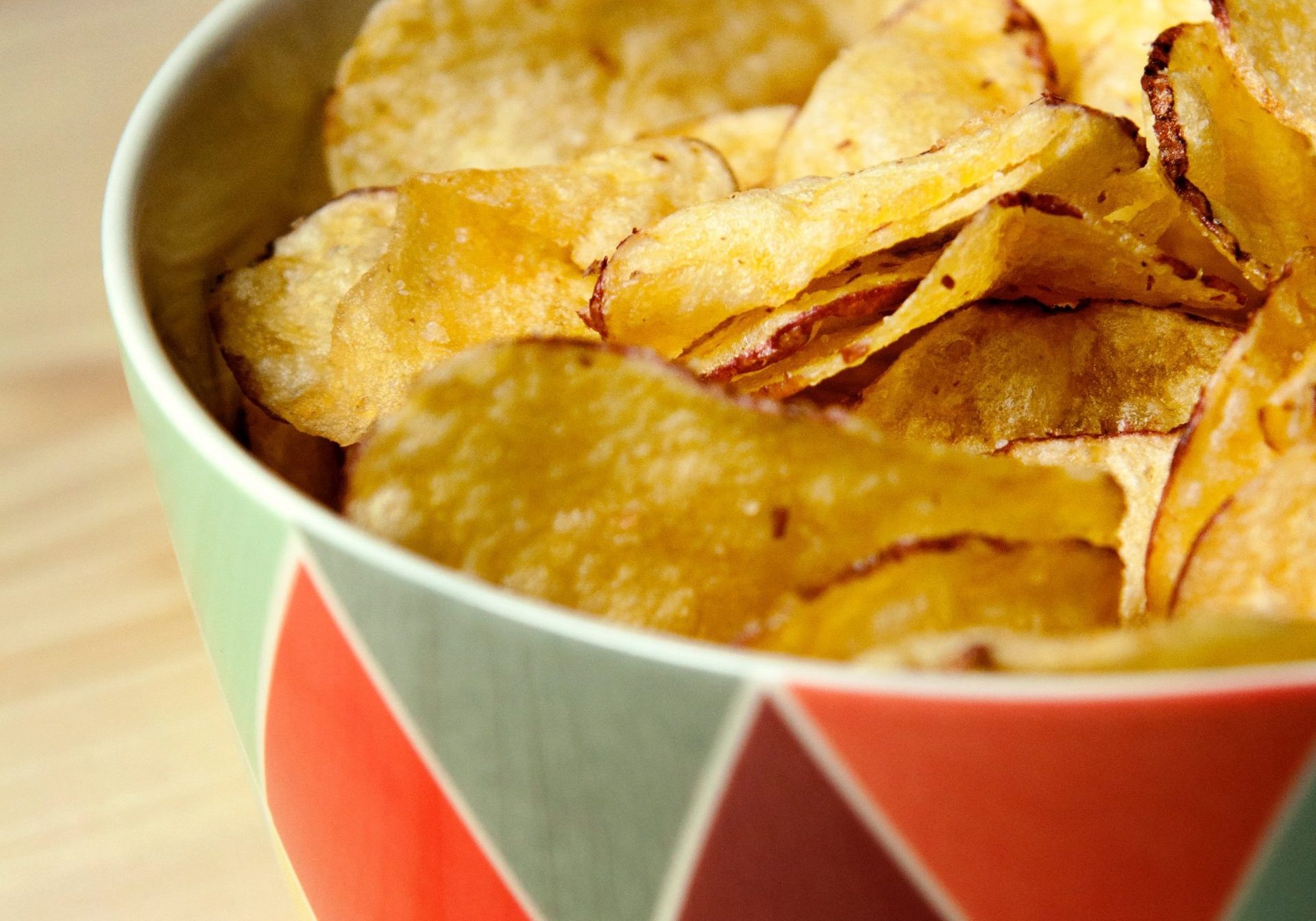 potato crisps chips in a colorful bowl on a wooden table