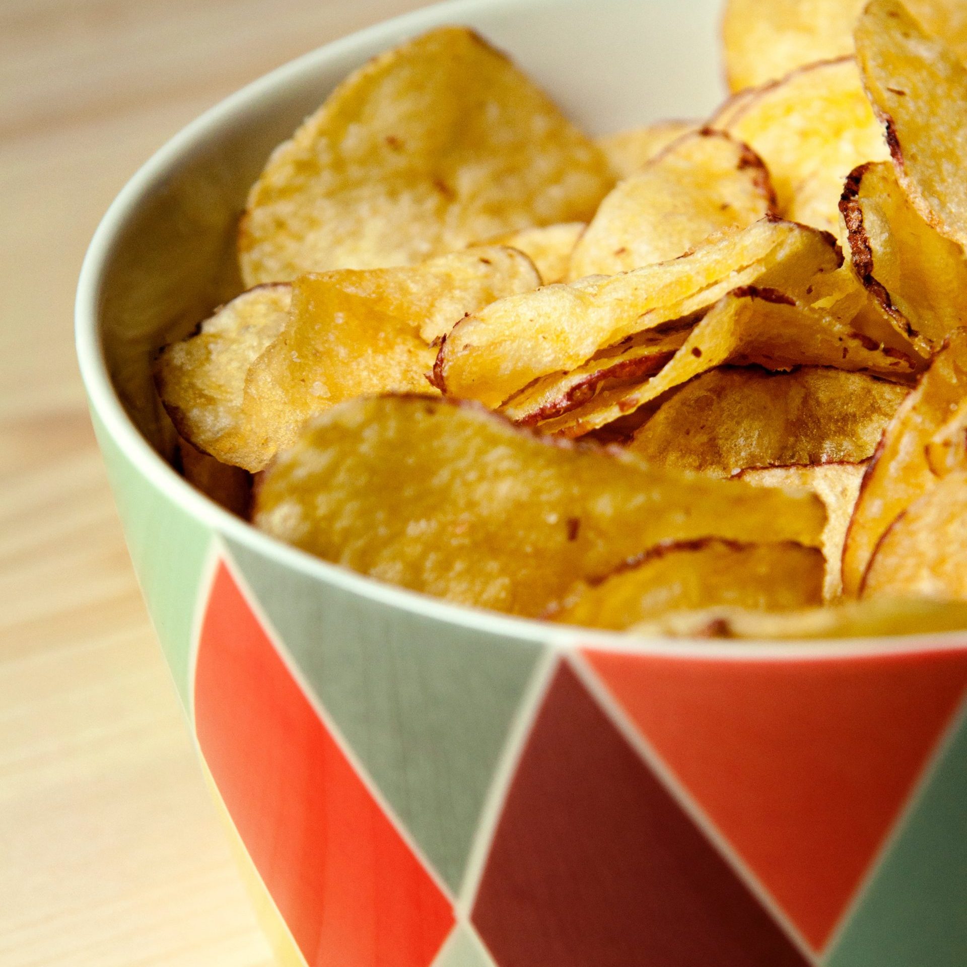 potato crisps chips in a colorful bowl on a wooden table