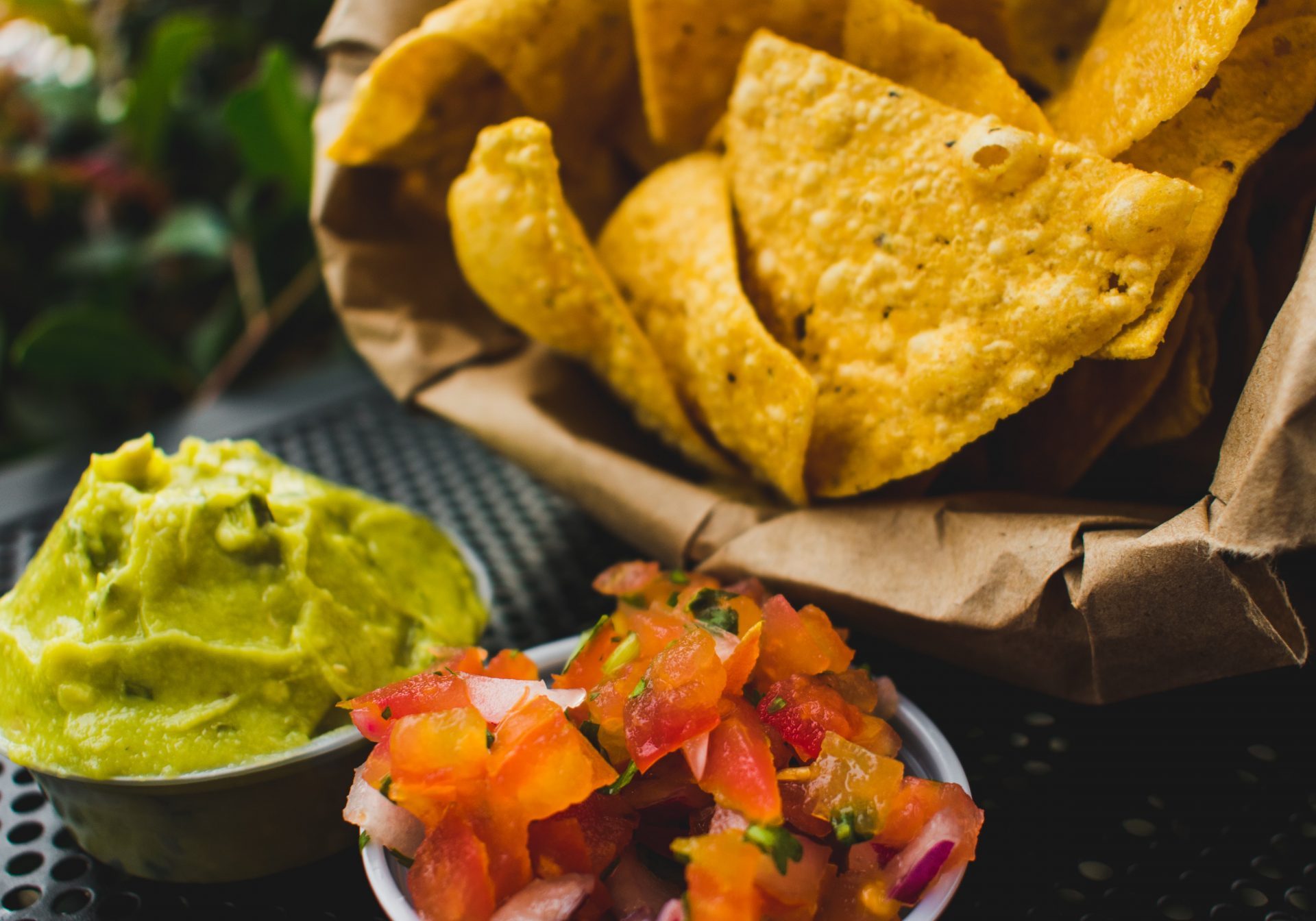 nachos with guacamole and tomatoes on a garden table