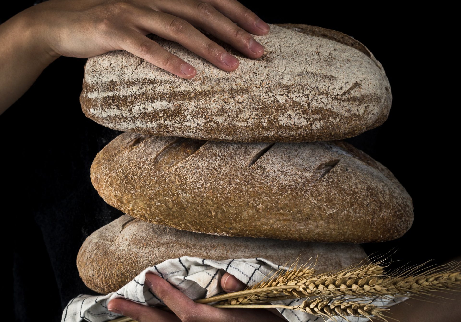 baking three different sorts of bread in. the hands of a woman, black background
