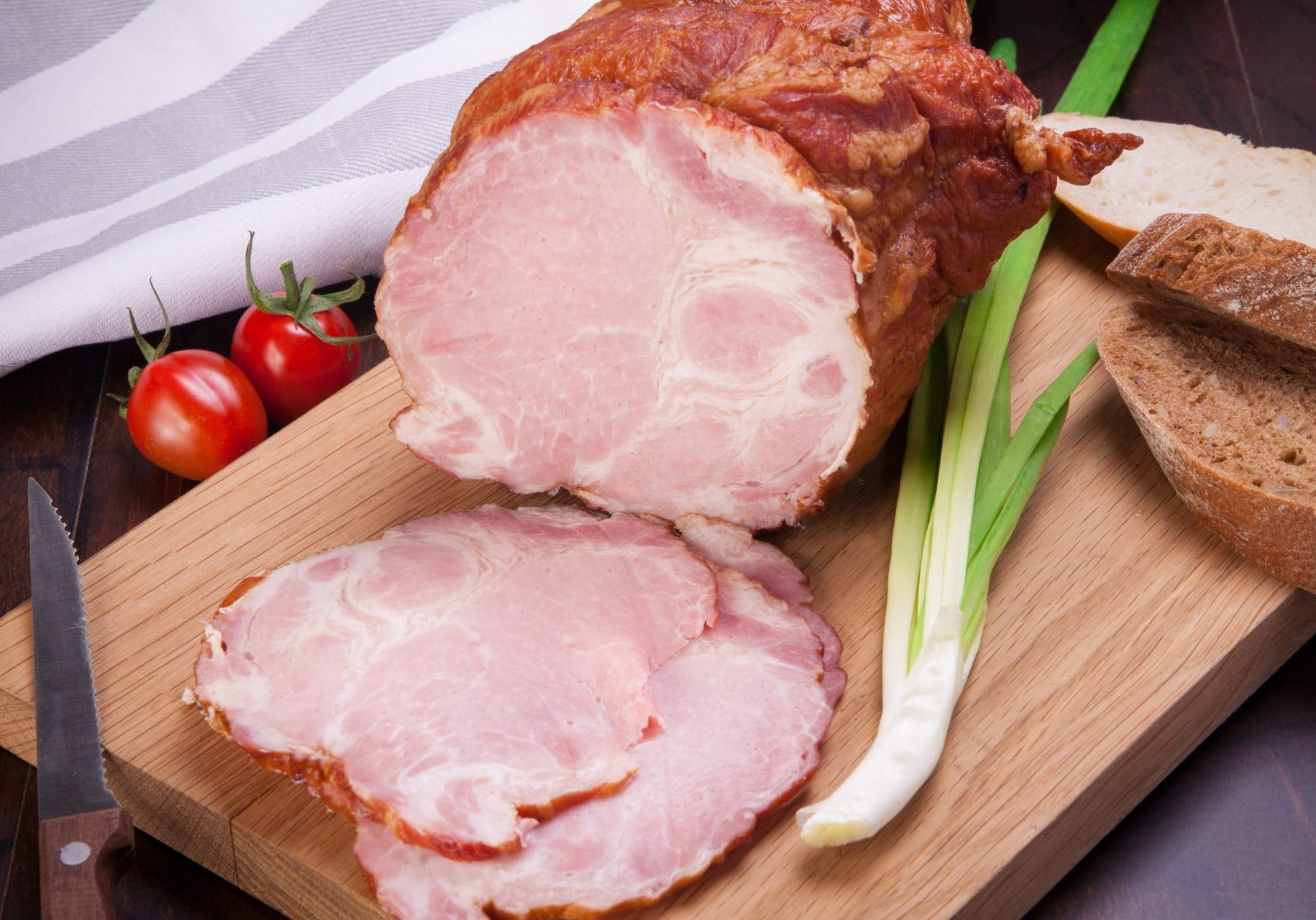 Ham meat with leek and tomatoes lying on a wooden board
